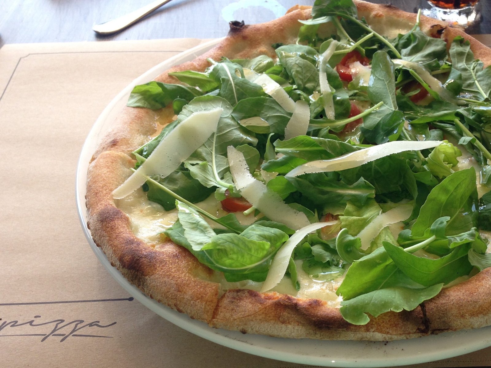 Una Pizza topped with fresh greens